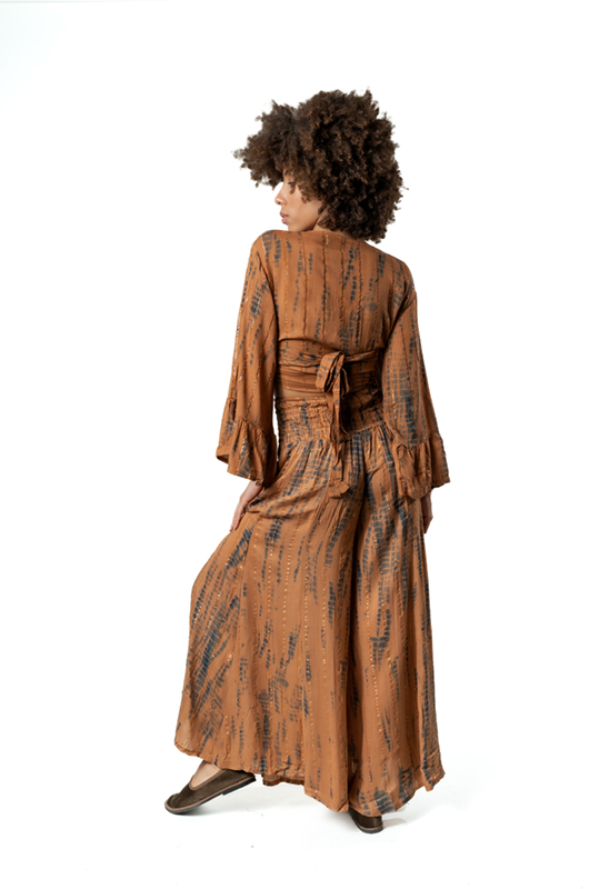 The model poses from an angled rear view, highlighting the movement of the maxi skirt and the bell sleeves.