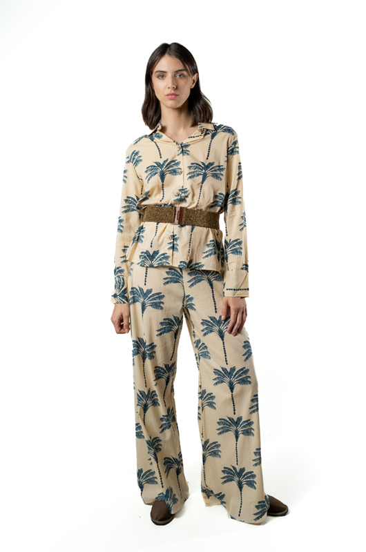 Front view of a model in a beige palm tree print co-ord set styled with a wide brown belt, standing in a studio.