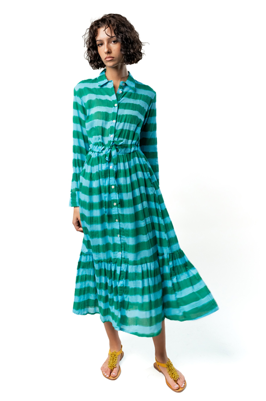 Woman posing in a green striped button-down midi dress with a flowy skirt, styled with yellow flat sandals.