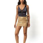 Model wearing mini pareo with golden eye motifs, styled over black swimsuit