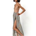 Model wearing long grey pareo with golden palm print tied at the waist.