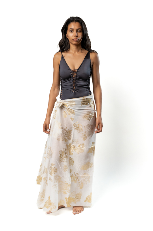 Woman wearing a full-length cotton pareo skirt with metallic print and a dark one-piece swimsuit.