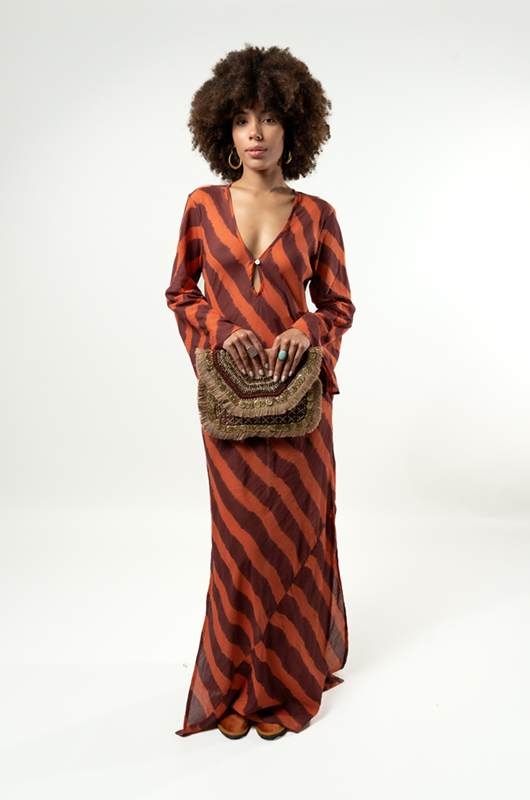 Beige clutch with black and gold geometric pattern, held behind the back