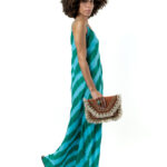 Side walking pose in green wave-patterned maxi dress, styled with a clutch.
