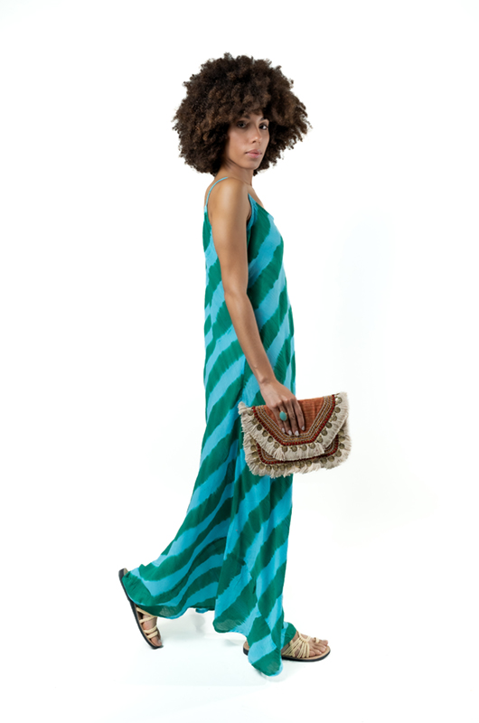 Side walking pose in green wave-patterned maxi dress, styled with a clutch.