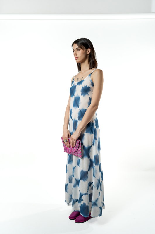Side view of the model holding a clutch, showcasing the relaxed flow and pattern of the maxi dress.