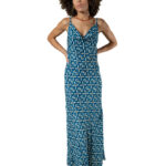 Model posing front-facing in a printed blue and cream slip dress with cowl neckline and sandals.