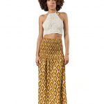 Model wearing a boho-chic mustard yellow long skirt with geometric patterns paired with a white crochet halter crop top, front view.