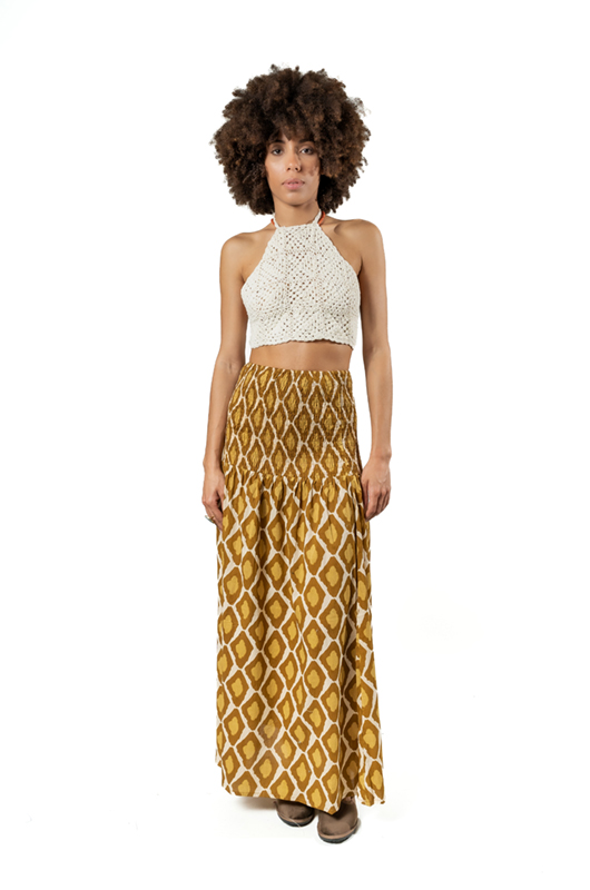 Model wearing a boho-chic mustard yellow long skirt with geometric patterns paired with a white crochet halter crop top, front view.