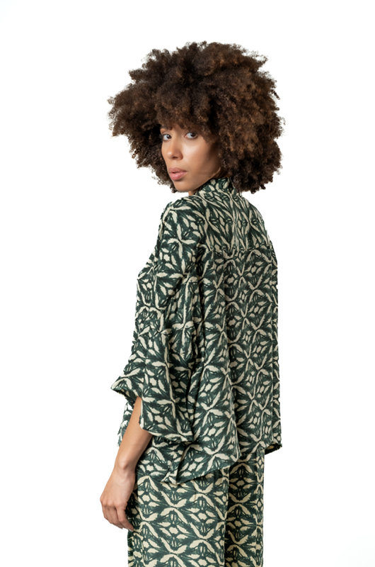 Close-up view of the model from the back, highlighting the sleeve and back detail of the green printed shirt.