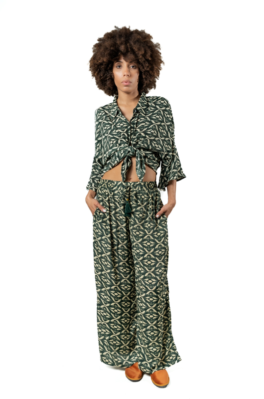 The same outfit with the shirt tied in the front for a cropped look, paired with the same green printed wide-leg pants.