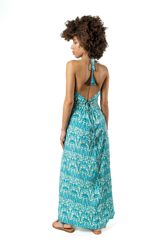 Back view of a woman wearing a turquoise patterned halter dress, showcasing the low back and tassel tie detail.