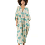 Model wearing a loose beige kaftan with turquoise green palm tree print, V-neckline and relaxed fit.