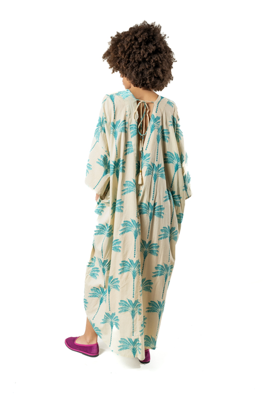 Back view of beige kaftan with green palm print, tie detail and tassels on open back.