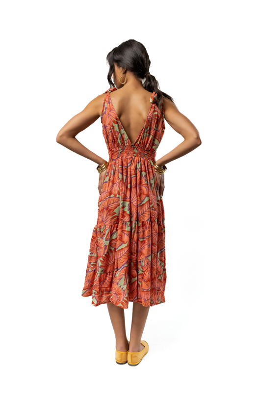 Rear view of a woman wearing an orange floral print midi dress with a deep V-back.