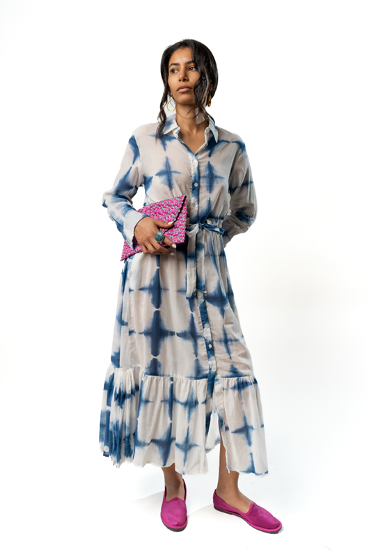 Woman wearing a long-sleeved button-down midi dress with blue tie-dye patterns, styled with a pink clutch and pink flats.