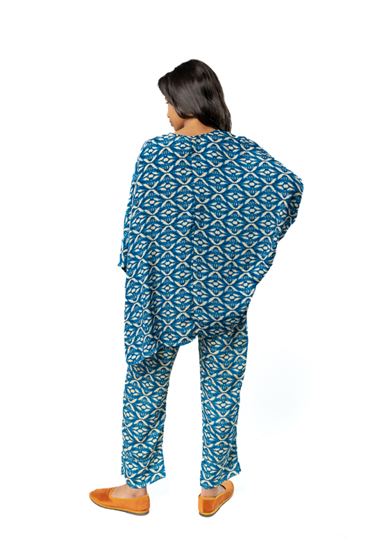 Model showing the back of a blue patterned kaftan-style outfit with loose pants.