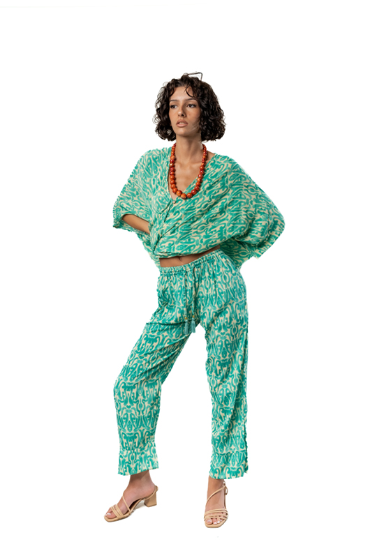 Model posing in a cropped green patterned kaftan-style top and high-waist matching pants, hands on hips.