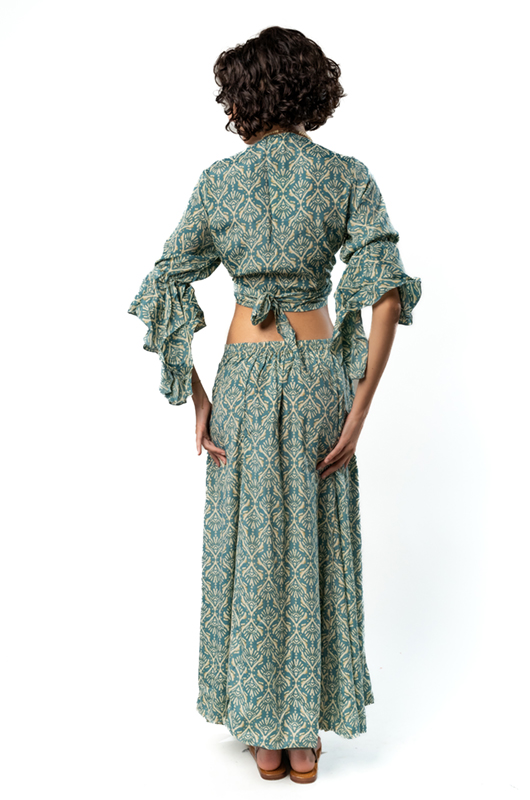 Back view of the green patterned blouse tied at the waist, showing ruffled sleeves and open back detail