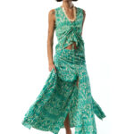 Model in a sleeveless green printed top with front tie and matching flowing skirt, walking forward as the skirt billows.
