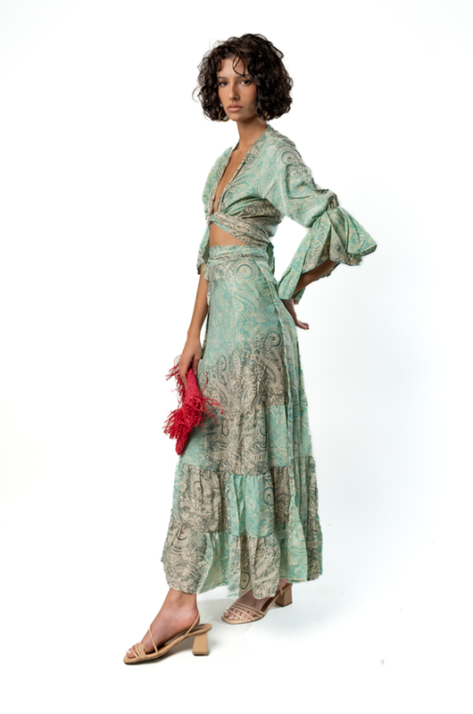 Side view of model wearing a mint green paisley wrap maxi skirt with flared tiers and matching crop top.