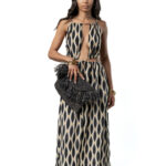Woman wearing a sleeveless black and ivory ikat print maxi dress with front cut-out, halter neckline and flowy skirt – boho chic summer dress.