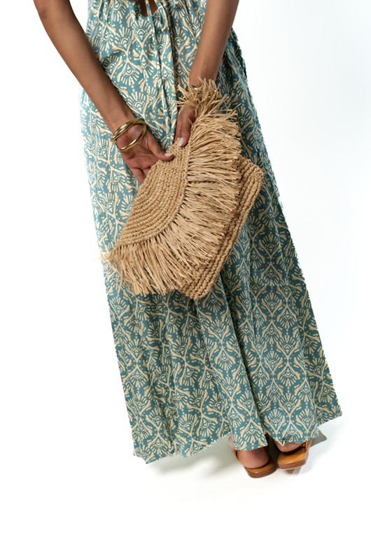 Close-up of the clutch and bottom half of the green patterned dress.