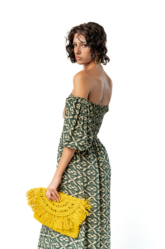 Detail of green off-shoulder ethnic print dress with woven yellow clutch and open back