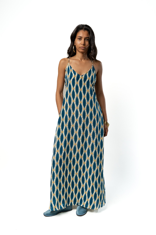 A front view of the blue patterned maxi dress with the model standing with hands in pockets.