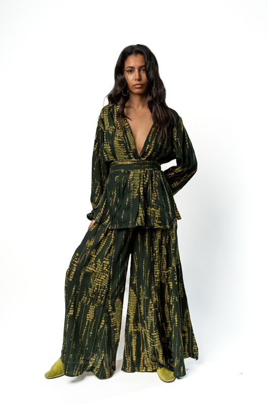 "Front view of a woman wearing a dark green two-piece set with a gold abstract print, featuring a deep V-neck wrap kimono-style top with a belt and wide-leg matching trousers."