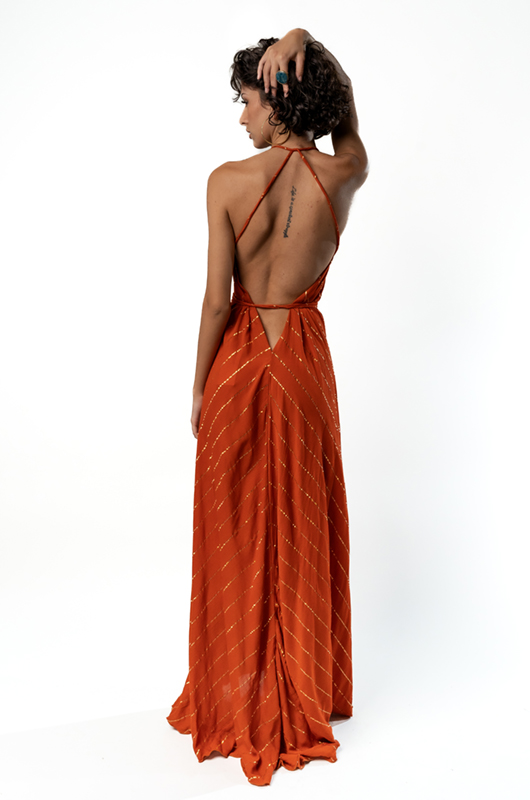 Back view of the model wearing the same dress, highlighting the open back design with thin straps and a tied waist.