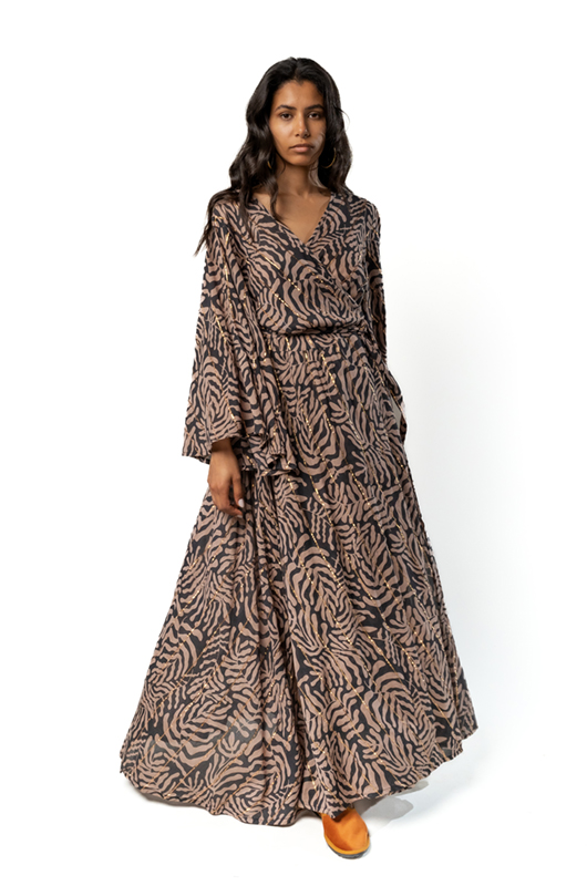 Model walking in a beige and black abstract leaf print maxi dress with flared sleeves, front angle.