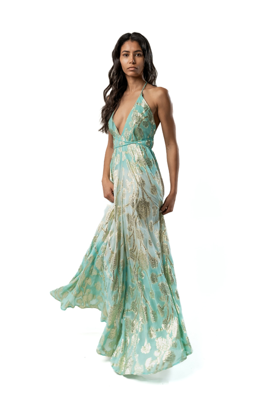 "Model in a turquoise and gold metallic halter maxi dress with a flowing skirt, without the kimono, showing the dress in motion."