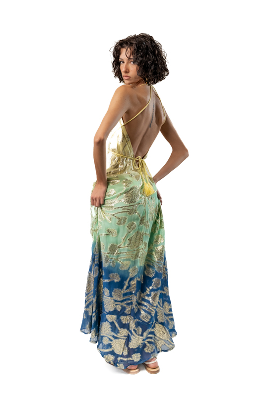 "Back view of an open-back ombre halter maxi dress in yellow, green, and blue with metallic gold floral patterns."