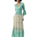 Long V-neck dress with a smocked waist and flared sleeves, featuring a turquoise top section and cream lower part with a gold geometric pattern.