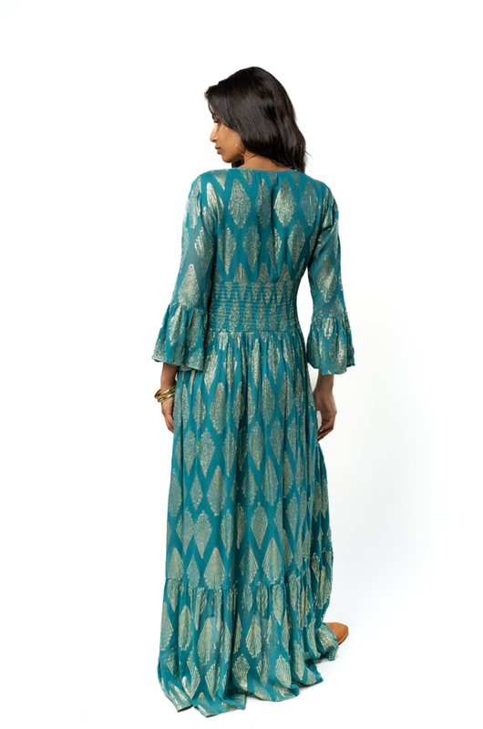 "Back view of a teal and gold bohemian dress with an elastic waist, flared sleeves, and long flowing skirt."