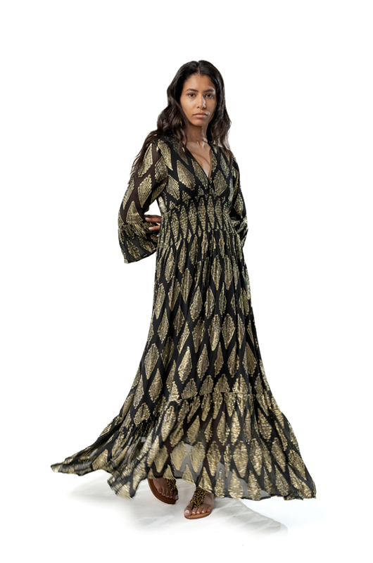 Flowing side view of a black maxi dress with gold geometric leaf patterns, V-neckline, and long flared sleeves.