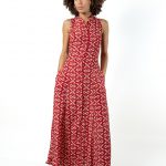 "Front view of a sleeveless, full-length red diamond-patterned dress with a collared neckline and button-down front, modeled by a woman with curly hair."