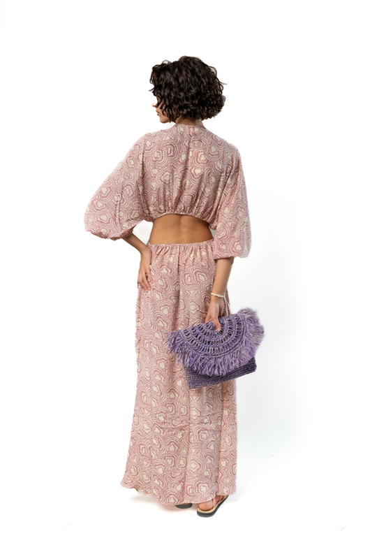 Back studio view of a one-shoulder beige maxi dress with blue palm print, showing a knotted draped detail on the side.