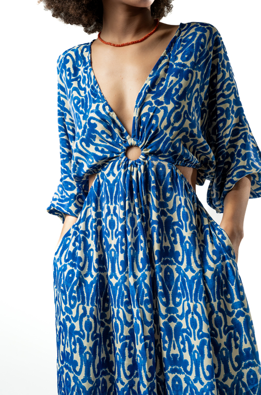 Alt text: Close-up view of the ring detail and cutout waist of a blue ikat print long-sleeved maxi dress.