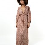 Front view of a woman wearing a long-sleeved V-neck bohemian maxi dress with a pink leaf pattern and a ring detail at the waist.