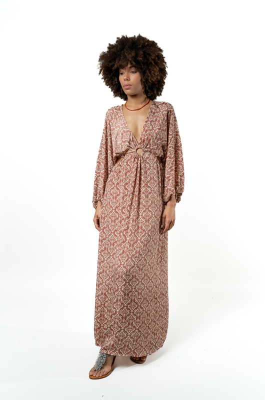 Front view of a woman wearing a long-sleeved V-neck bohemian maxi dress with a pink leaf pattern and a ring detail at the waist.