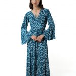 "Model wearing a long wrap dress in blue diamond pattern with flared sleeves"