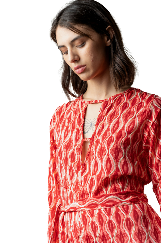 Close-up of the upper front of a red curves print jumpsuit showing the keyhole neckline and belt detail.