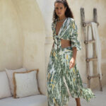 Lightweight blouse with green and yellow leaf print, deep V-neckline, and front tie closure, styled with puffed sleeves."