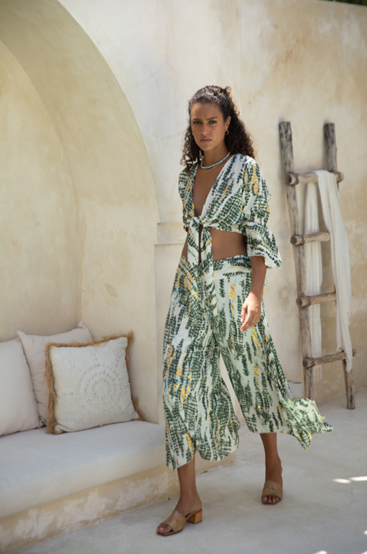 Lightweight blouse with green and yellow leaf print, deep V-neckline, and front tie closure, styled with puffed sleeves."
