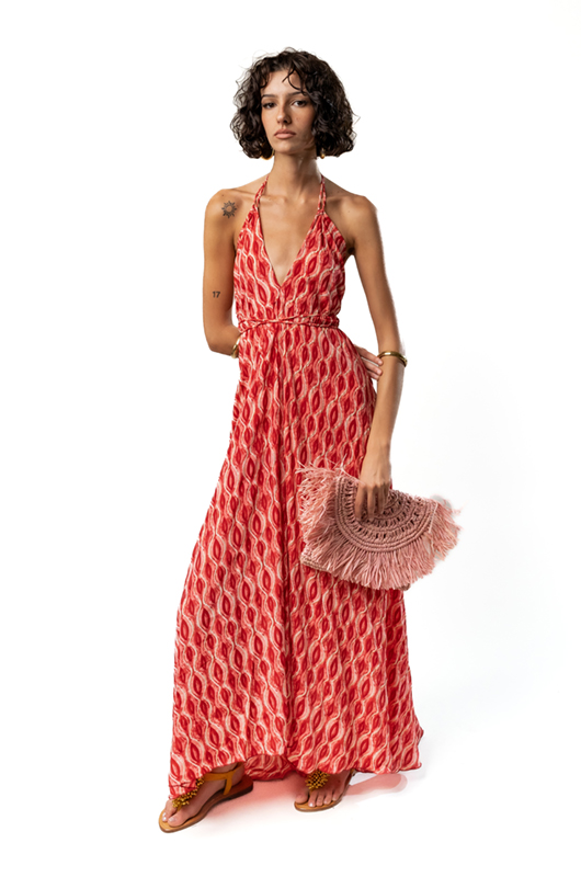 Woman wearing a black and beige patterned crop top and matching long skirt, holding a yellow beaded clutch bag, posing sideways.